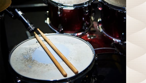 A pair of drum sticks resting on a snare drum