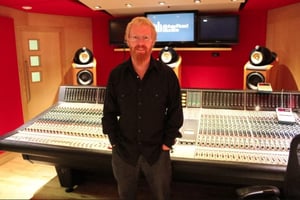 Drew Morgan standing in front of a large mixing console at Abbey Road Studios