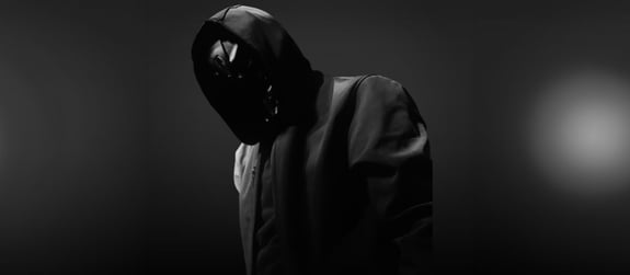 A black and white press shot of Grimmvulture wearing a hooded jacket and mask