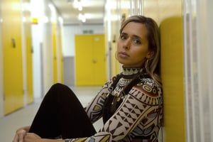 A press photo of Kayla Painter sat in an empty corridor