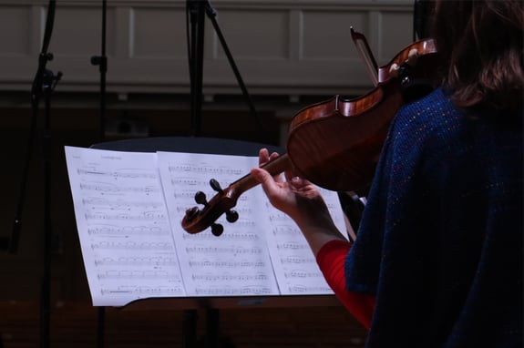 A violin player performing from a piece of score