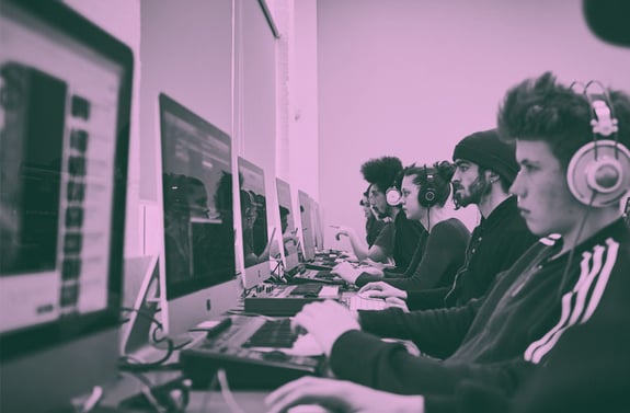 A class of students working in an iMac suite with a pink gradient overlay on the image